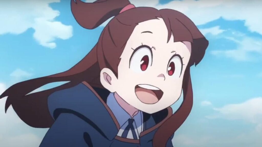 Akko dans sa tenue de sorcière, souriant dans le ciel dans l'anime Little Witch Academia