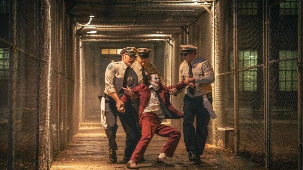 Le Joker (Joaquin Phoenix) emmené par des gardiens de prison dans Joker Folie à Deux